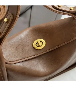 Detail of vintage dark brown leather bag featuring an oval golden turn-lock closure