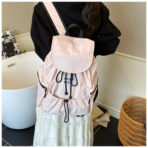 Detail of light pink drawstring backpack with woven label and functional side zipper pocket
