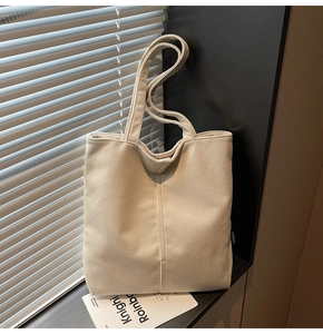 Close-up of off-white corduroy tote bag texture with minimalist brand label detail