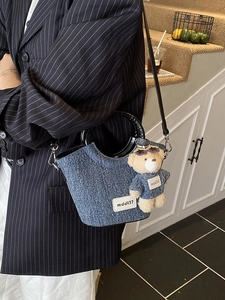 Borsa a secchiello in denim con ciondolo a orsetto e tracolla su blazer a righe