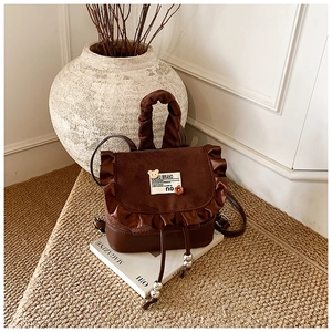 Detail of retro leopard backpack featuring satin ruffles, bear charm and ruched handle