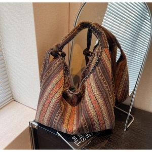 Ethnic woven tote bag with colorful geometric patterns and knot handle detail on desk