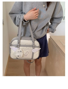 Close-up of a grey JK style tote bag featuring star prints, wing details and a plush bear charm