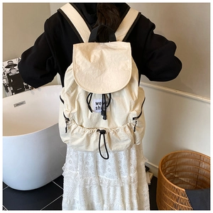Detail of cream drawstring backpack showing nylon texture and stylish brand label