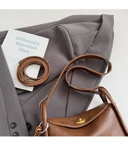 Detail of vintage brown leather pillow bag featuring golden twist lock and textured finish