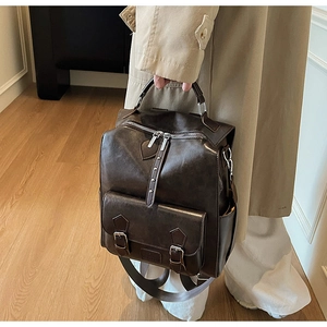 Detail view of vintage dark brown faux leather backpack with metal buckle front pocket