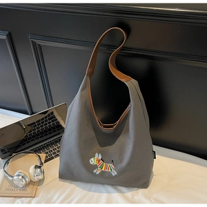 Detailed close-up of embroidered zebra pattern and brown leather straps on canvas tote bag
