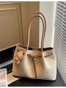 Minimalist large capacity khaki tote bag with plush bear charm in a modern office setting