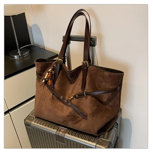 Detail of coffee brown suede tote bag with leather straps and boho beaded charm
