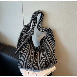 Detail view of black and white woven hobo bag with geometric patterns and soft strap