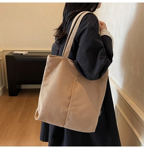 Detail of khaki corduroy tote bag showing thick ribbed texture and side brand tag