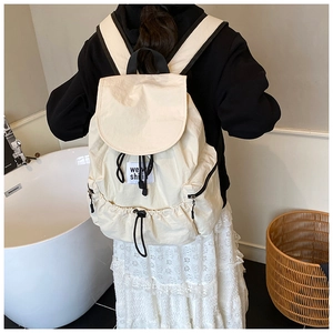 Close-up of cream nylon backpack featuring drawstring closure and side zipper pocket