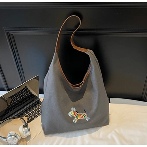 Detail of embroidered canvas tote bag with brown leather handles and a colorful donkey motif