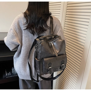 Detail of vintage matte black leather backpack with silver buckles and adjustable straps