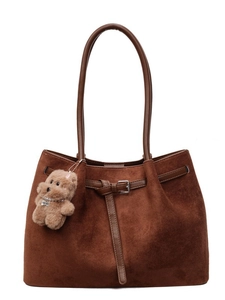 Brown matte tote bag with thin shoulder straps and plush dog charm on white background