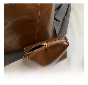 Detail view of the brown leather tote set with matching pouch and gold zipper accents