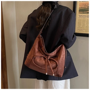 Vue de dos d'un modèle portant un sac hobo en daim marron au style rétro épuré