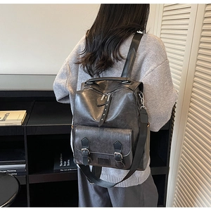 Detail view of dark grey vintage PU leather backpack with a large buckled front pocket