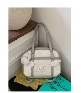 Chic white tote bag featuring star patterns and a cute plush bear charm on a wooden shelf