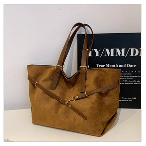Close-up of brown suede tote bag featuring premium leather straps and vintage gold hardware