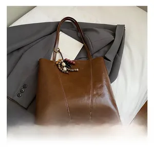 Close-up of brown vintage tote bag with glossy leather texture and colorful wooden beads