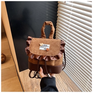 Detail of mini brown suede backpack with frill trim, cute bear charm and metal drawstring