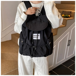 Detail view of black nylon backpack with drawstring closure and large front utility pocket