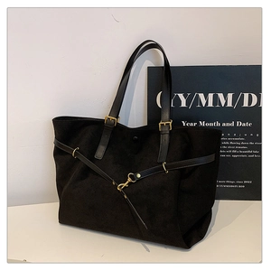 Close-up of black matte tote bag with adjustable handles and elegant gold metal buckles