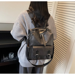Vintage dark gray backpack with adjustable straps worn by model in a modern interior