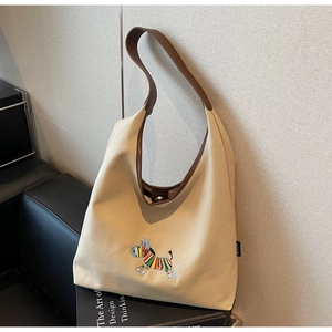 Detail of colorful zebra embroidery on beige canvas tote bag with leather straps