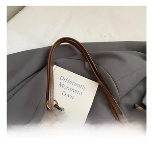 Close-up of deep brown leather tote handle with bronze ring and colorful beaded charm