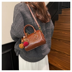 Detailed view of a brown vintage barrel bag with fuzzy charms worn cross-body