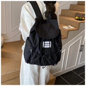 Detail view of a black drawstring backpack with water-resistant fabric and side pockets