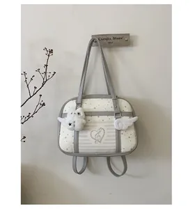 Detail view of cream leather backpack with wing decor and plush charm on minimalist wall