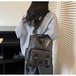 Detail view of retro faux leather backpack featuring buckled pockets and nylon straps