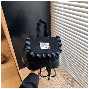 Close-up of black mini backpack featuring ruffle edges and a decorative teddy bear patch