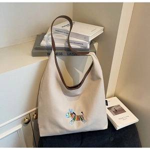 Detail of colorful zebra embroidery and brown leather strap on cream canvas hobo bag