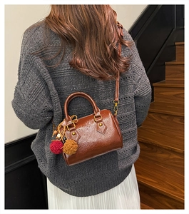 Brown vintage cylinder Boston bag with fur charms and shoulder strap in casual setting