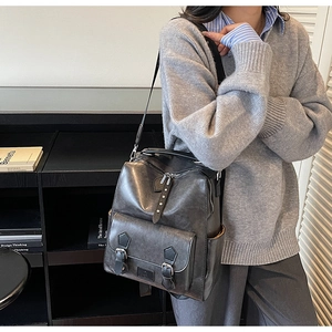 Detail view of dark grey vintage faux leather backpack with metal rivets and buckle pockets