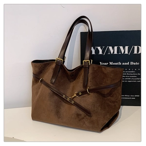 Detail of vintage brown suede tote bag with leather handles and gold metal buckles