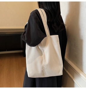Close-up of off-white corduroy tote bag showing vertical texture and wide shoulder strap
