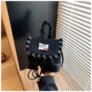 Detail of black mini backpack featuring ruffled edge, brand patch and cute 3D ornaments