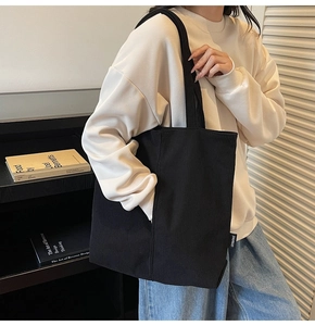 Close-up of black corduroy tote bag showing vertical ribbed texture and brand label
