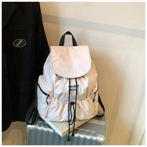 Detailed view of light pink nylon backpack featuring drawstring closure and side pockets