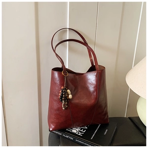 Detailed view of dark red tote bag with glossy leather texture and colorful charm