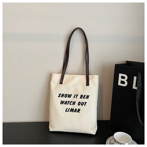 Détail du sac cabas en toile minimaliste avec anses en cuir marron et lettrage artistique