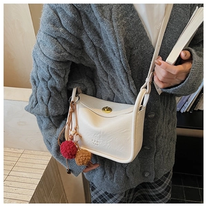Detail of off-white lychee leather crossbody bag with PAN TOR logo and bicolor fur pompom
