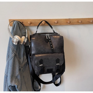 Detail of vintage faux leather backpack featuring front flap pockets and canvas straps