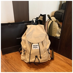 Detail of beige nylon backpack with flap drawstring closure and brand label