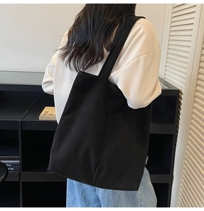 Detail of black corduroy tote bag with vertical ribs and a white side label for women